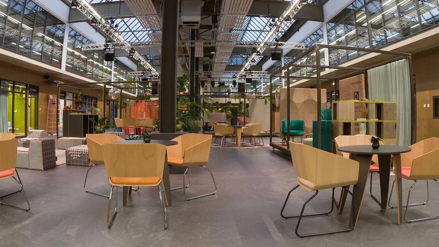 Runde Bistrotische, dahinter der Lounge-Kubus mit grünen Samtsesseln