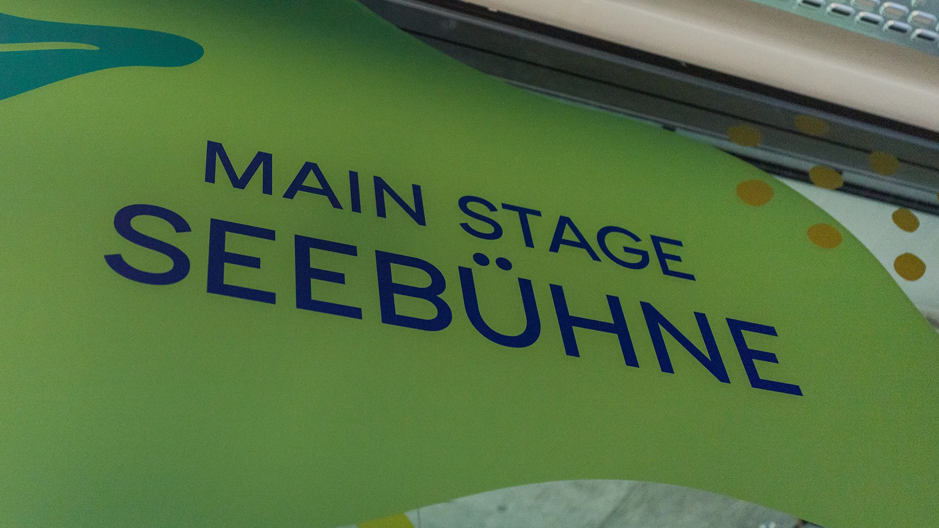 „Main Stage Seebühne“ auf einer organisch gestalteten, grünen Wandfläche mit Punkten und Formen im Hintergrund.